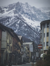 Buildings and snowcapped mountains against sky