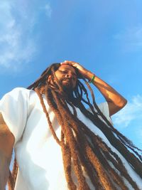 Low angle view portrait of mature man with dreadlocks against blue sky