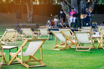 Many white deck chairs with tables for dinner in lawn is surrounded by shady green grass 