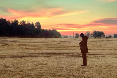 Rear view of woman standing on field against sky