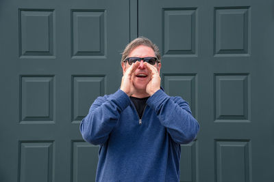 Portrait of man shouting while standing against closed door