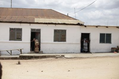 People standing outside house against sky