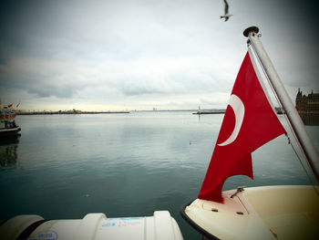 Turkish flag on boat in river against sky