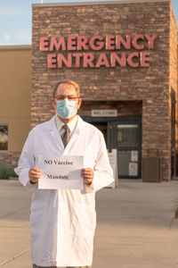 Portrait of smiling doctor holding text outdoors