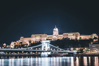 Illuminated bridge over river at night