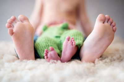 Low section of mother with baby on rug