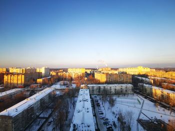 High angle view of snow covered buildings against sky during sunset
