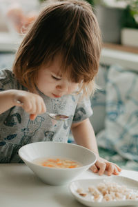 A little girl is sitting at the kitchen table eating soup. high quality photo