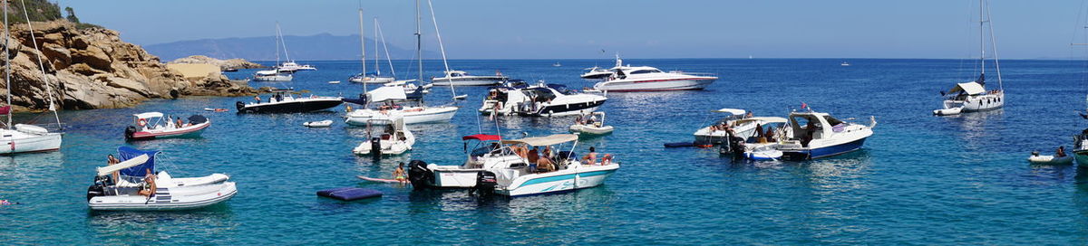 Boats sailing in sea against clear sky