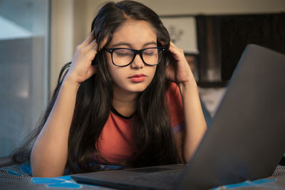 Portrait of young woman using laptop at home