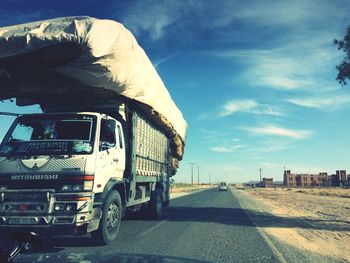 Vehicles on road against sky in city