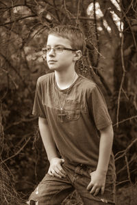 Boy posing against dried plants in forest