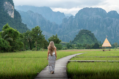 Rear view of woman walking on field