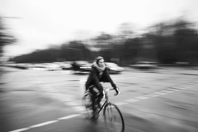 Young woman riding bicycle on road in city