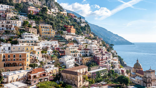 Aerial view of townscape by sea against sky