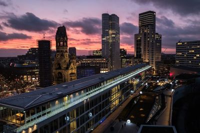 Illuminated buildings in city against sky during sunset