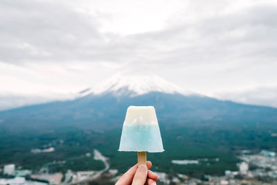 Person holding umbrella against mountain