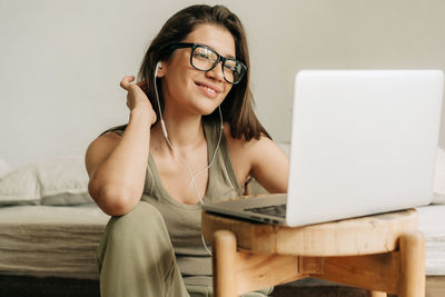 Young woman using laptop while sitting on sofa at home