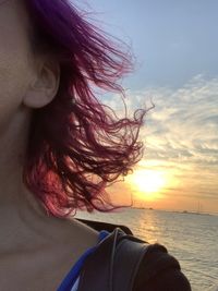 Portrait of beautiful woman by sea against sky during sunset