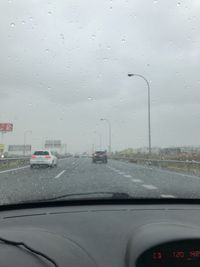 Cars on road seen through wet glass window