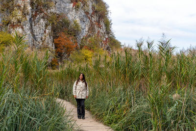 Young woman walking on wooden path surrounded by reed in plitvice lakes national park in croatia