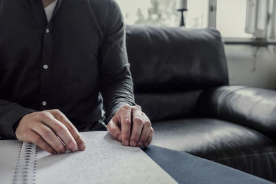 Midsection of man sitting on sofa