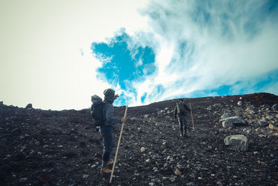 Low angle view of friends on mountain against sky