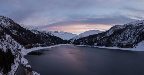 Scenic view of lake by mountains against sky during sunset