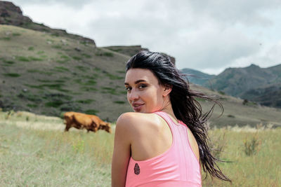 Portrait of young woman looking over shoulder while sitting on field