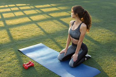 Side view of young woman exercising on field