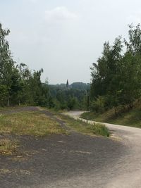 Road by trees against sky