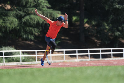 Athlete with prosthetic leg running on sports track