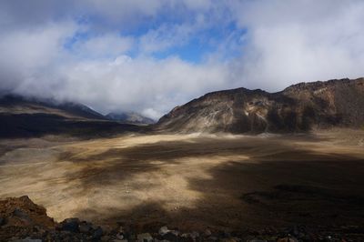 Scenic view of arid landscape against sky and clouds 