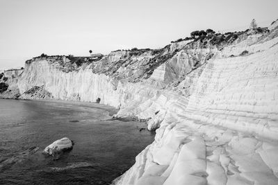 Rock formations by sea at scala dei turchi