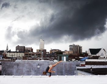 Man standing on city street against cloudy sky