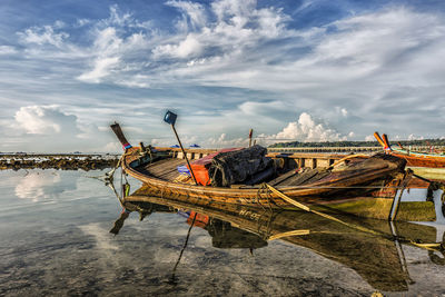 Fishing boats moored on sea against sky