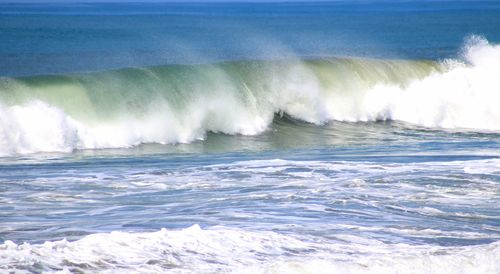 Waves splashing in sea against sky