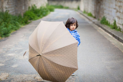 Little handsome baby boy playing with umbrella outdoor