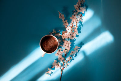 Directly above shot of coffee with with cherry blossom over colored background