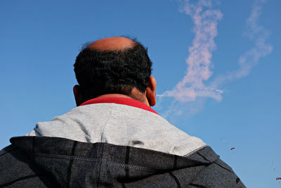 Woman standing on rock against blue sky