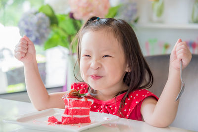 Portrait of cute girl having cake while sitting at table