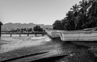 Boats moored on beach against clear sky