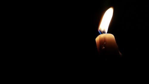 Close-up of lit candle in darkroom