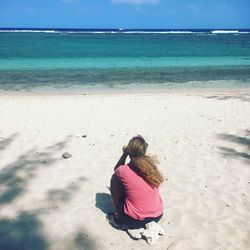 Rear view of woman sitting on beach