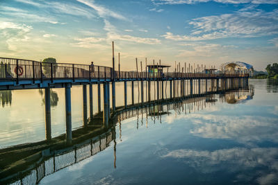 Pier on river against sky during sunset