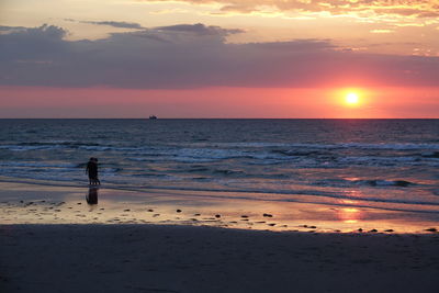 Silhouette person on beach against sky during sunset