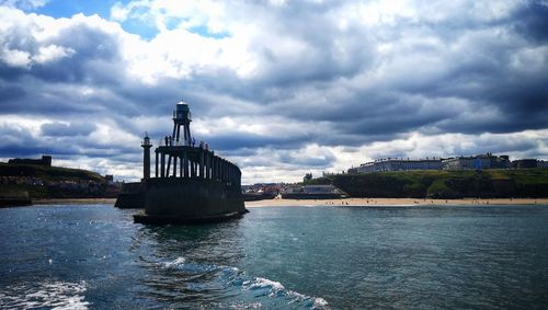 Lighthouse by sea against sky