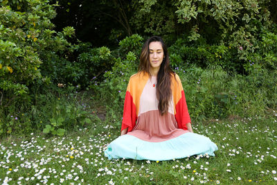 Portrait of young woman sitting against plants