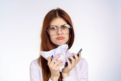 Portrait of young woman holding thermometer against white background