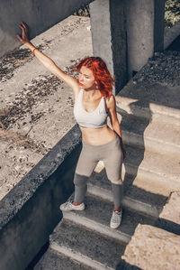 Woman in running gear, crop top and shorts, stretching her body and preparing for a run, or cooling